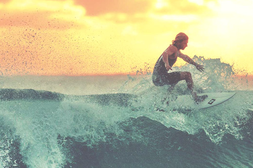 surfer riding a wave with sunset vision in the background