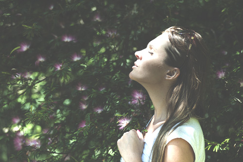 A woman is taking a deep breath outside to release stress and increase mindfulness