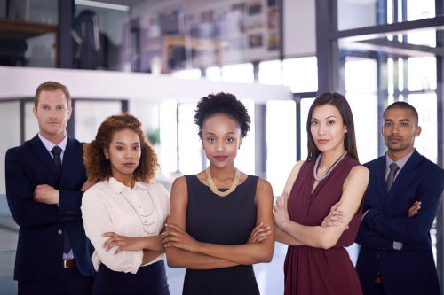 The group is diverse in terms of gender and ethnicity, and they are dressed in formal business attire, suggesting a professional setting