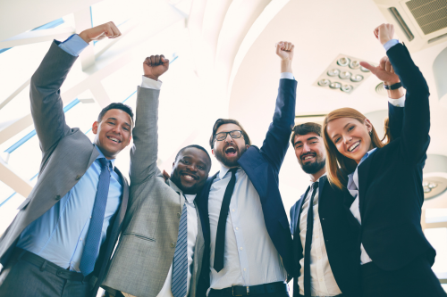 A group of five diverse professionals dressed in business attire standing close together